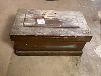 Top and side angled view of rectangular vintage wooden chest with a worn surface, paint marks, and raised paneled top.