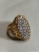 Full three-quarter view of the ring showing oval stone cluster and side engraving