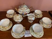 Full set arranged on table with 6 cups and saucers, teapot, creamer, and sugar bowl with lids.