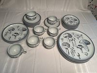 Full set of mushroom-themed dinnerware including plates and cups arranged on table