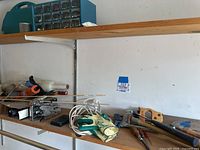 Shelf holding various tools including screwdrivers, gloves, parts caddy, and hand saws