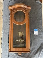 Front view of vintage wooden mini grandfather clock showing full case with glass panels and visible clock face and pendulum.