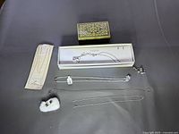 All items arranged on black surface: necklace box, decorative box, chains, earrings