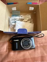 Front view of Canon PowerShot SX260 HS camera showing lens, model, and accessories in box