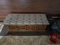 Full view of the Lane cedar chest with a wooden base and a cushioned upholstered padded top with a patterned fabric.