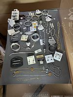Overview of the entire jewelry lot including various bracelets, earrings, and necklaces laid flat on a dark surface