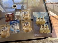 Several Glade air freshener refill packages and two white plastic plug-in holders displayed on glass table.