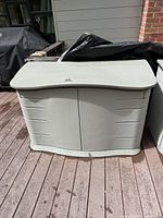 Outdoor heavy duty plastic storage container closed on wooden deck