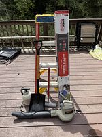 Full view of outside tools on wooden deck including ladder, boxed gutter guard, shovel, sprayer, squeegee, and blower.
