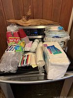 Paper party goods including red Solo cups, white plastic cups, plastic utensils, napkins, and stacked paper plates on a stovetop.