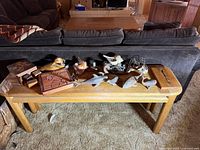 Lot displayed on wooden bench with various carved wooden animal figurines, puzzle boards, jewelry boxes, and wood burl piece.