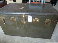 Full front view of the McBrine baggage trunk showing metal riveted construction and brass latches and lock.