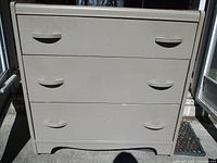 Front view of the vintage painted chest of drawers showing three drawers with integrated curved pulls and dove grey paint.