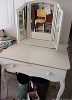 Front view of vintage painted wooden desk with closed drawer and attached tri-fold mirror showing overall shape and design.