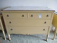 Front view of the painted yellow chest of drawers showing two small top drawers and two larger bottom drawers on turned legs with castors