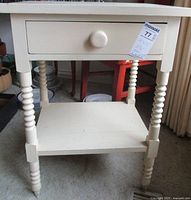 Full frontal view of the painted side table showing drawer, spool-turned legs and lower shelf