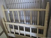 Yellow painted spool-turned headboard leaning against wall