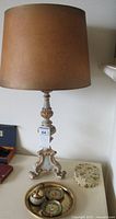 Vintage Italian Florentine table lamp on a tripod base with a brown lampshade and decorative gold and green body.