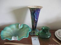 Front view of all three items on surface: Murano bowl, green ruffled vase, and tall multi-color lusterware vase with damage at base.