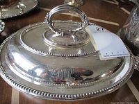 Close-up view of the vintage silverplate covered serving dish lid showing the handle and monogram engraving.