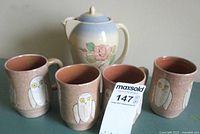 Photo showing four snowy owl mugs arranged with the Susie Cooper coffee pot behind them on a surface.