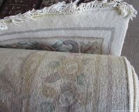 Folded end showing cream wool pile, pastel floral border and fringe