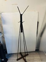 Full view of the 61-inch tall wooden coat rack with a cross-legged hardwood base and multiple metal hooks at the top against a plain background.