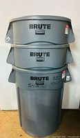 Stacked view of three gray ULINE BRUTE trash bins showing brand and condition.