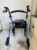 Front view showing blue frame, black cushioned seat, backrest, and wheels.