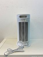 Front view of the white Honeywell HEPA air purifier showing cylindrical shape and vertical slats with power cord in front.
