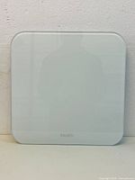 Front view of the iHealth white digital body weight scale against a white wall, showing clean surface and brand logo.