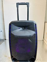 Front view of ION portable party speaker with purple LED light glowing through speaker grille, retractable handle extended.
