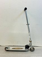 Full side view of Razor kids scooter showing metal frame, deck with logo, black grips on handlebar, and wheels