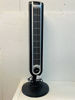 Front view of the Lasko 36-inch tower fan showing the black and silver design with the power cord wrapped at the base.