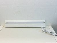 White rectangular LED light bar with frosted diffuser and attached white power cord, shown from front view.