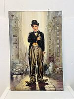 Front view of realistic canvas wall art featuring Charlie Chaplin in classic attire with a city street background.