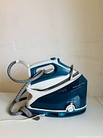 Side view of Rowenta Compact Steam Extreme steam iron with base showing hose connection, handle, and control knob.