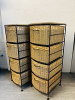 Front and side angled view of two storage cabinets with black metal frames and woven seagrass drawers, one natural tan and the other whitewashed.
