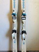 Pair of alpine skis with bindings visible from the side showing toe and heel pieces.