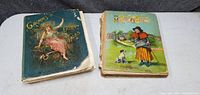 Two illustrated antique children's books side by side on white surface