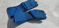 Pair of blue safety gloves laid flat, showing padded palms and fingers, extended cuffs.