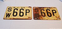 Front view of two vintage NJ 1950 license plates with characters SW 66P, one plate heavily rusted.