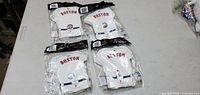 Photo showing four packages of Boston Red Sox napkins in original sealed packaging laid on a table.