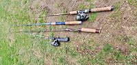 Four fishing rods laid on grass, showing reels and cork handles