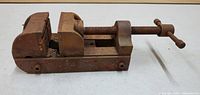 Side view of rectangular metal table vise showing fixed jaw, adjustable jaw, and threaded screw with T-handle.