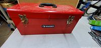 Closed red metal Husky toolbox with black handle and two metal latches.