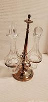Front view of the vintage silver plated condiment holder with two glass cruets and decorative stoppers.