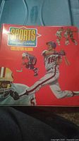 Red binder labeled 'Sports Trading Cards Collector Album' with sports player illustrations on the cover.