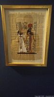 Framed Egyptian painting on papyrus showing two figures and Egyptian hieroglyphics on natural papyrus backing.