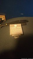 Black Facon straight razor and unopened Facon razor blades box positioned on black surface.